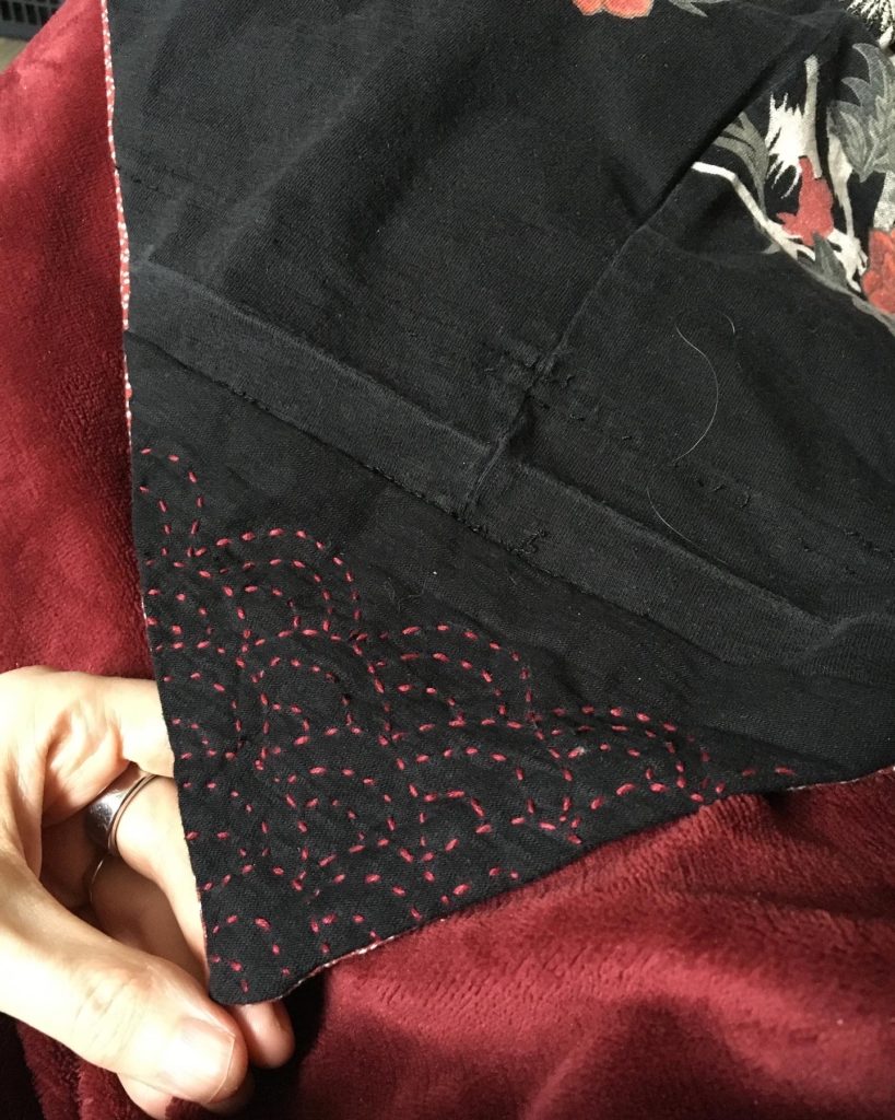 A detail of the red sashiko stitching on the front of the shawl.
